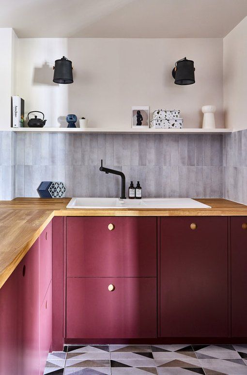 a burgundy kitchen with lower cbainet,s an open shelf and butcherblock countertops, black fixtures
