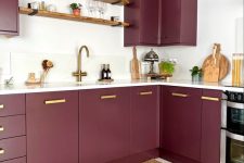 a burgundy plum kitchen with white countertops and a backsplash, open shelves and gold handles