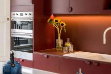 a chic contemporary burgundy kitchen with built-in lights and a white kitchen island with white countertops