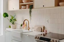 a chic kitchen in dove grey and light-colored plywood, with white countertops and a white stacked tile backsplash