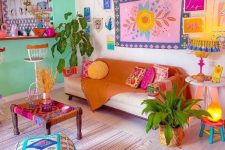 a colorful dopamine decor living room with a green accent wall, a neutral sofa with bold pillows, a colorful gallery wall and an embroidered pouf