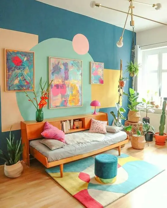 a colorful dopamine living room with a blue accent wall with geo prints, a daybed with a bookshelf, potted plants and bright artwork