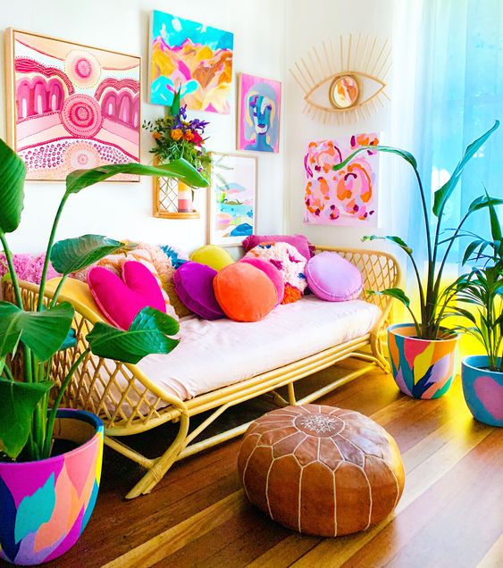 a colorful dopamine living room with a rattan sofa and colorful pillows, a colorful gallery wall, colorful pots and a brown pouf