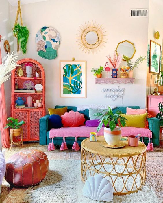 a colorful dopamine living room with a teal sofa and colorful pillows, a coral sideboard, greenery and bold decor
