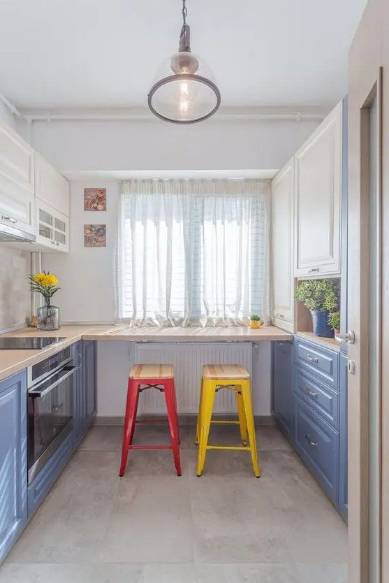 a colorful kitchen with cobalt blue and white cabinets, a breakfast bar with colorful stools, a pendant lamp and potted greenery
