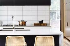a contrasting contemporary kitchen with black cabinets, white stone countertops and a white stacked tile backsplash