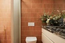a cool bathroom clad with skinny terracotta tiles, with a shower space, a large vanity and a large mirror is very warm and welcoming