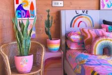 a dopamine decor bedroom with a bed done with extra bold bedding, pink nightstands, potted plants and bright artwork