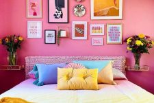 a dopamine decor bedroom with bold pink walls, a bed with a knit headboard, bright bedding, a bold gallery wall