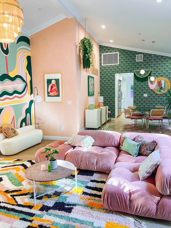 a dopamine decor living room with Peach Fuzz walls, a pink sectional, a coffee table, a bold printed rug, bold accent walls