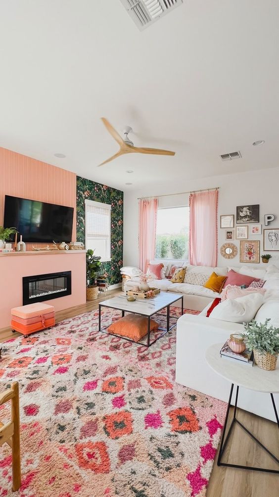 a dopamine decor living room with a Peach Fuzz accent, floral wallpaper, a white sofa, printed pillows and a bold printed rug
