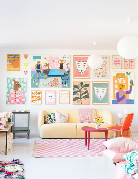 a dopamine decor living room with a pale yellow sofa, an orange chair, a colorful gallery wall, a bold rug and pillows