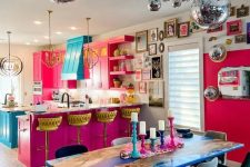 a dopamine decor space with a hot pink kitchen, a turquoise hood and kitchen island, an electric blue table and disco balls over it