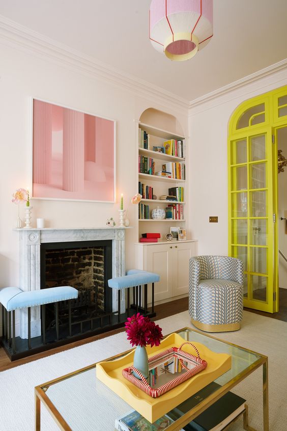 A dopamine living room with a fireplace and blue stools, built in shelves and a cabinet, a printed chair and an artwork
