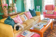 a dopamine living room with green walls, a yellow sofa, an orange table and pink chairs, a printed rug and refined decor