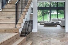 a farmhouse space with chevron floors, a staircase with the same floor and pendant lamps plus netural light