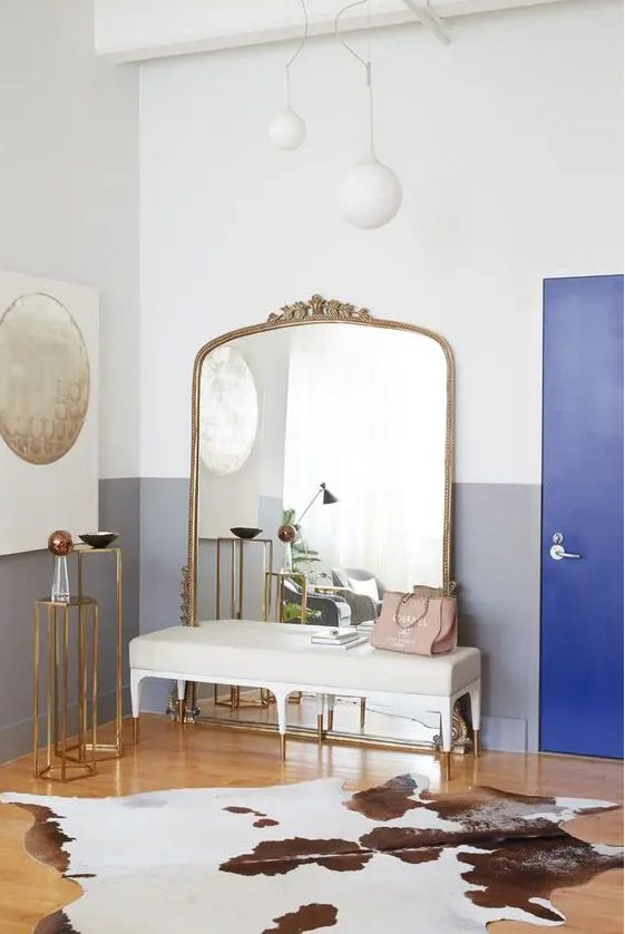 a glam entryway with a large mirror in a brass frame and soem other brass accents