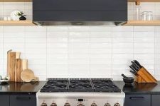 a graphite grey kitchen with wooden shelves and a white stacked tile backsplash is very chic and bold