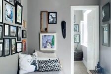 a grey narrow bedroom with a small bed, a crate for storage and gallery walls and a pendant lamp