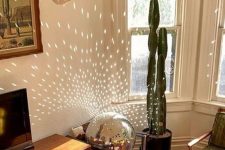 a large disco ball placed on the chair opposite the window brings light and shine to the space and makes it brighter