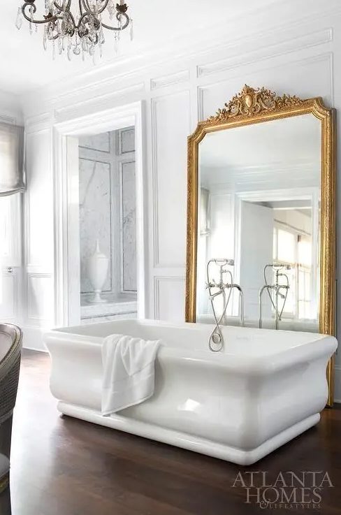 a large mirror in a refined gilded frame is a great decor idea for a bathroom
