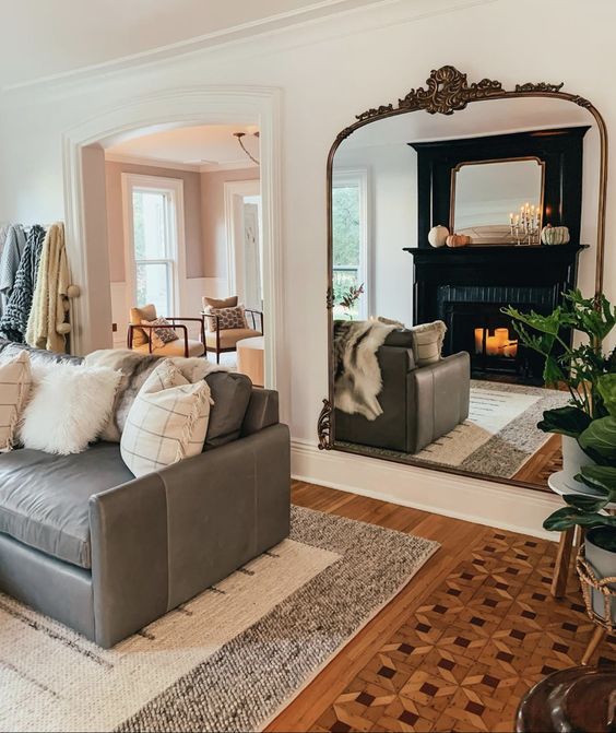 a large mirror in an ornated frame hanging opposite the sofa is a cool solution to make the space larger