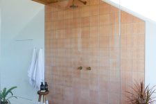 a large shower space with a wooden ceiling, terracotta tile, potted plants and natural light is amazing