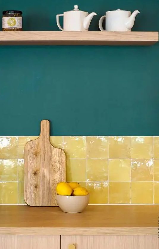 A light stained kitchen with dark green walls and a bold and shiny yellow tile backsplash plus an open shelf is a lovely idea