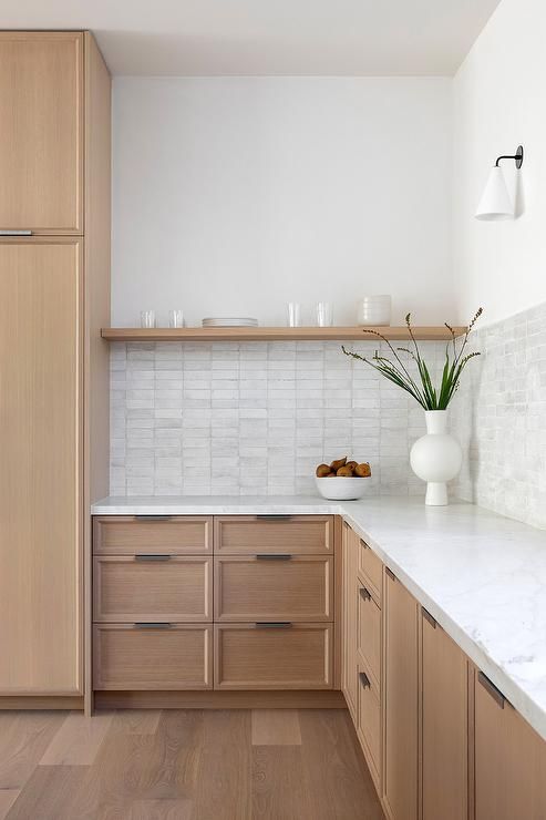 A light stained oak kitchen with white countertops, an open shelf and a stacked tile backsplash is cool