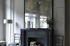 a living room is given chic and a vintage feel with an oversized antique mirror and a faux fireplace with books