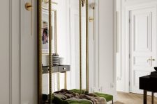a luxurious entryway with a green velvet bench, an oversized mirror in a refined gilded frame and a dark console table