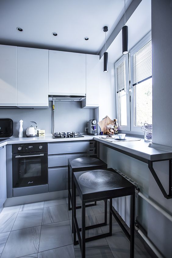 a minimalist grey and white kitchen with a windowsill table and tall black stools is a cool space