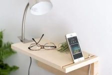 a minimalist wooden plank floating nightstand for holding just a couple of things and charging your phone