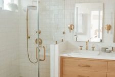a modern bathroom done with white Zellige and hex terracotta tile, a stained vanity and brass fixtures is very welcoming