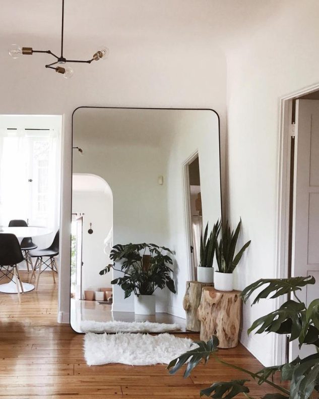 a modern boho nook with an oversized mirror in a sleek black frame, potted plants and a faux fur rug is chic and cozy