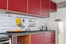 a modern deep red kitchen with a white subway tile backsplash, grey stone countertops, open shelves is a catchy space