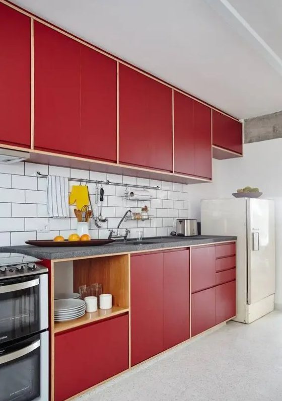 a modern deep red kitchen with a white subway tile backsplash, grey stone countertops, open shelves is a catchy space