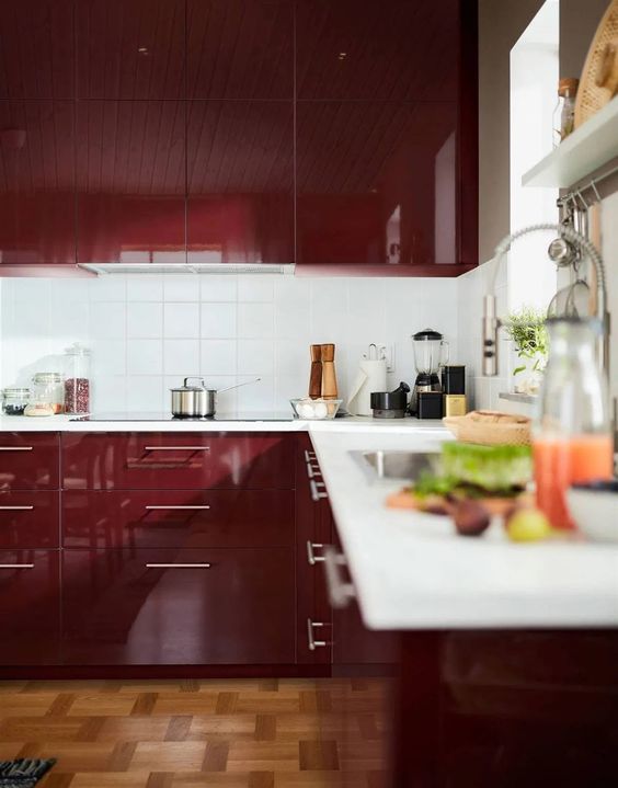 a modern glossy burgundy kitchen with a white square tile backsplash and white stone countertops is an awesome space