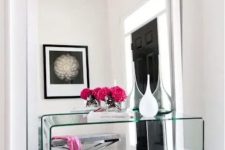 a modern mirror with no frame takes the whole wall and a glass console complements the look