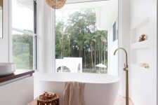 a modern white bathroom with windows for a view, niches, a tub, a chandelier, a stool and a floating vanity is cool