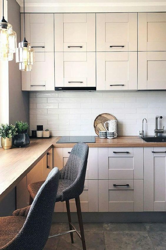 a neutral kitchen with a white backsplash, butcherblock countertops and a countertop as a windowsill and a table plus grey stools