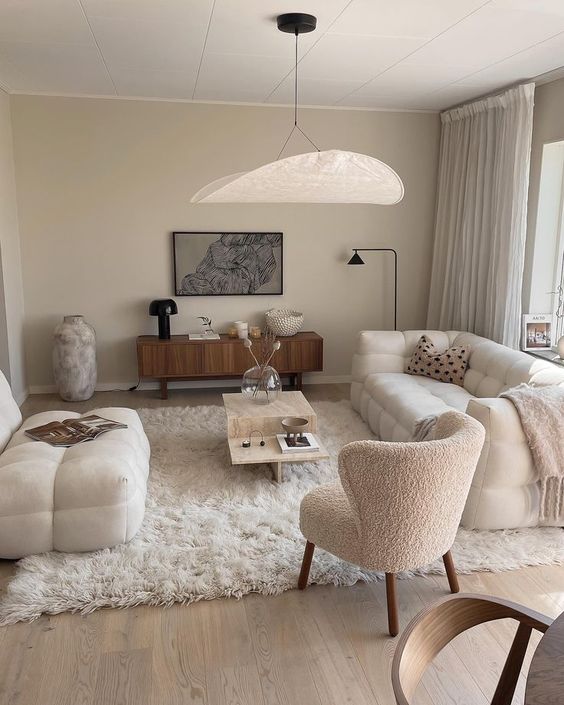 a neutral living room with a white sofa, a matching loveseat, a white boucle chair, a coffee table, a stained credenza