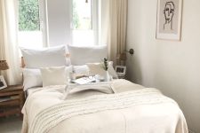 a neutral narrow bedroom with a bed and neutral bedding, stained nightstands, a pendant lamp and jute rugs plus some decor