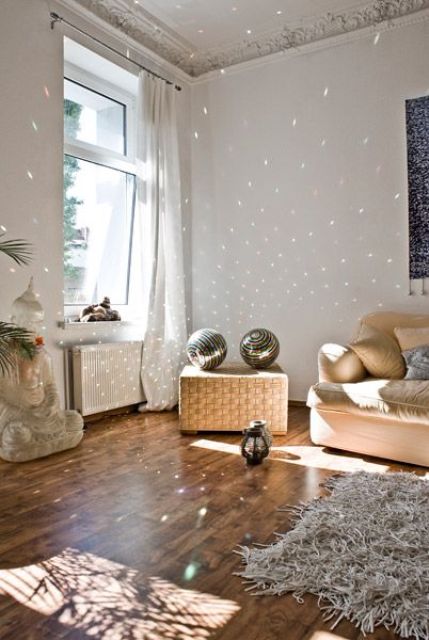 a neutral yet eclectic living room with a tan sofa, a chest with disco balls, a statue, a rug and lots of light