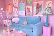 a pink dopamine living room with a pastel blue sofa, a bold gallery wall, a pink coffee table, a pink chandelier and a blue lamp