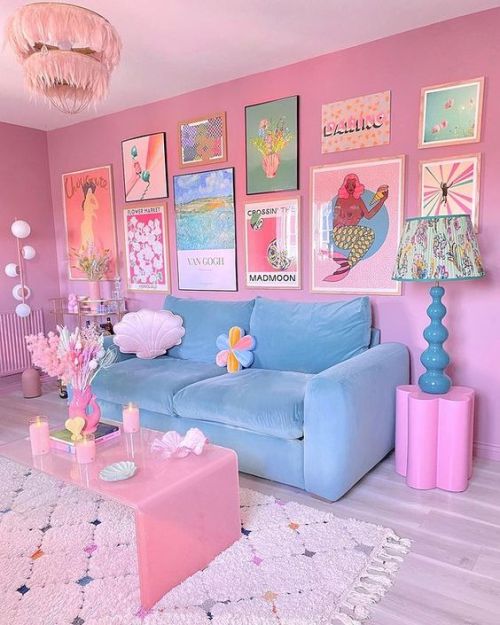 a pink dopamine living room with a pastel blue sofa, a bold gallery wall, a pink coffee table, a pink chandelier and a blue lamp