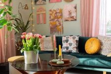 a pretty dopamine-infused living room with light grene walls, a dark green sofa, printed pillows, a bold gallery wall, a pink and orange rug