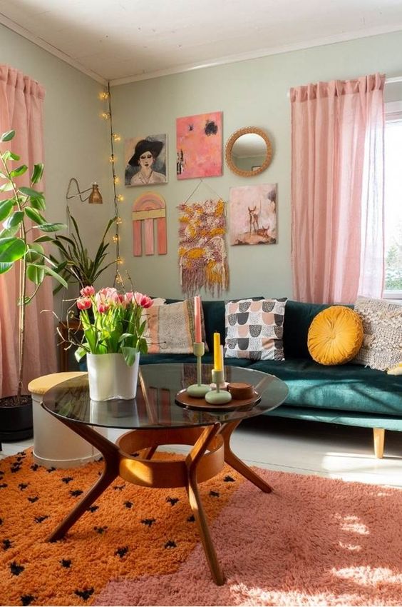 a pretty dopamine-infused living room with light grene walls, a dark green sofa, printed pillows, a bold gallery wall, a pink and orange rug