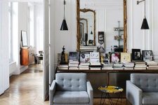 a refined Parisian living room with an oversized mirror in a gilded frame, a table with books and chic furniture
