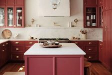 a refined burgundy kitchen with shaker cabinets, white countertops, gold fixtures and chic sphere pendant lamps